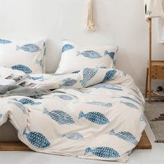 a bed with blue fish on it in a room next to a white wall and rug