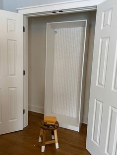 an empty room with white doors and a stool in front of the door that is open