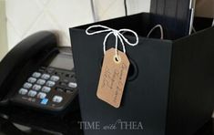 a black bag with a brown tag on it sitting next to a phone and telephone