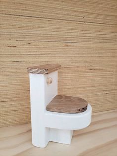 a white toilet sitting on top of a wooden floor next to a wood paneled wall