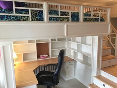 there is a desk and chair under the stairs in this lofted room with built - in bookshelves