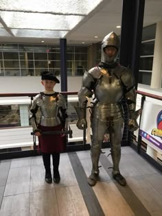 two people dressed in knight costumes standing next to each other on the floor at an indoor mall