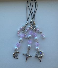 a necklace with beads and charms hanging from it's side on a white surface