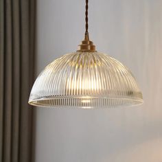 a clear glass light hanging from a ceiling fixture in a room with white walls and curtains