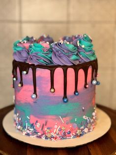 a colorful cake with chocolate icing and sprinkles on it sitting on a table