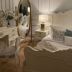 a bedroom with a white bed, dresser and mirror in it's center area