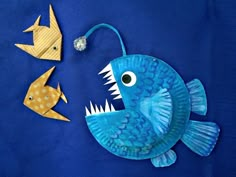 two paper fish and one goldfish on a blue background