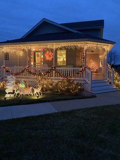 a house covered in christmas lights and decorated with wreaths on the front porch is lit up at night