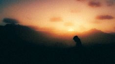 the silhouette of a person standing in front of a sunset