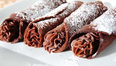 three chocolate desserts on a white plate with powdered sugar