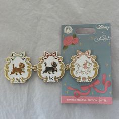 three pin badges are sitting next to each other on a white sheet with pink flowers