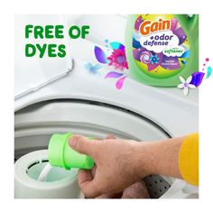 a hand is holding a green container over a washing machine with free of dyes