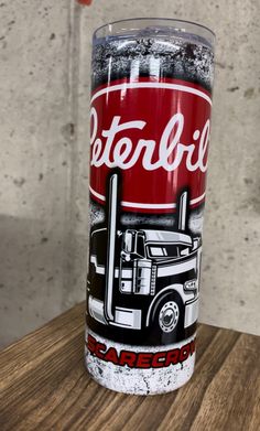 a close up of a can of soda on a wooden table with a concrete wall in the background