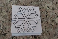 a snowflake cut out of paper sitting on top of a marble countertop