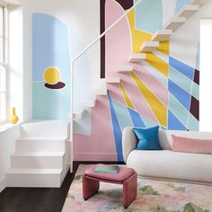 a living room filled with furniture and paintings on the wall next to a stair case