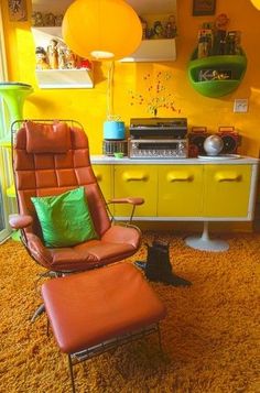 an orange chair and ottoman in a room with yellow walls, flooring and furniture