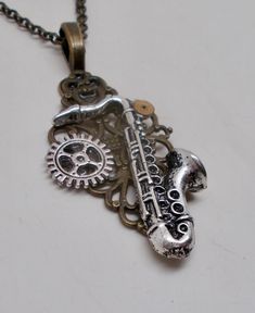 "Awesome steampunk necklace of saxophone and   watch gears mounted on a Victorian filigree. The size is about 1 1/4\" by 1\" and it has 24\" antique brass chain. All my jewelry come in a nice gift box. More steampunk necklaces in my shop  www.etsy.com/shop/slotzkin" Steampunk Jewelry Ideas, Steampunk Necklaces, Victorian Filigree, Steampunk Pendant, Watch Gears, Steam Punk Jewelry, Steampunk Necklace, Steampunk Jewelry, Steam Punk