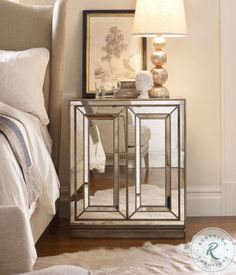 a mirrored cabinet with a lamp next to it on a rug in front of a bed