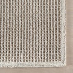 a beige and white rug on top of a wooden floor