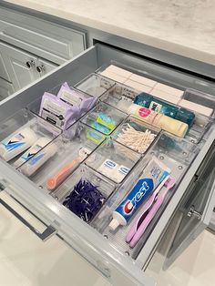 an open drawer with toothbrushes and other hygiene products in it on the counter