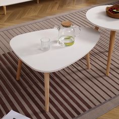 two white tables with drinks on them in a living room next to a striped rug