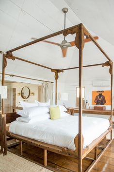 a bed with white sheets and pillows in a bedroom next to a wooden flooring