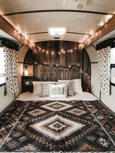 a bed in a trailer with lights strung from the ceiling