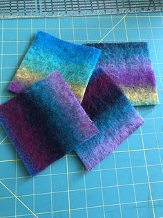 three pieces of felt sitting on top of a blue cutting board next to a ruler