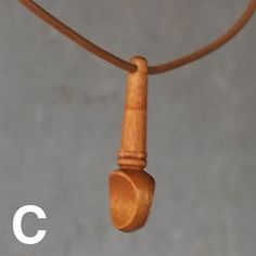 a wooden necklace hanging from a leather cord with the letter c on it's end