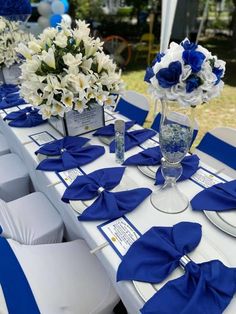 the table is set with blue and white napkins, silverware, and flowers