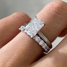 a woman's hand with two engagement rings on top of her finger and the ring is