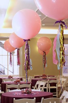 balloons and streamers fill the air above tables at a party with purple tablecloths