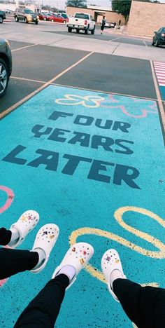 two people standing in front of a sign that says four years later on the sidewalk