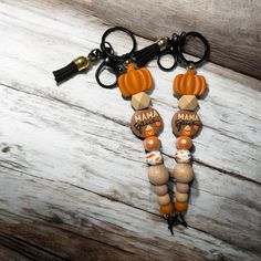 a pair of key chains with charms attached to them on a wooden table next to a pair of scissors