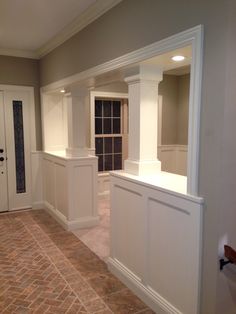 an empty room with white columns and brick flooring