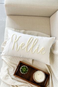 a white pillow with the word hello on it next to a candle and a tray