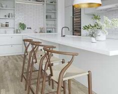 a kitchen with white counters and wooden stools