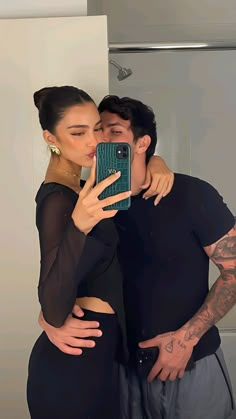 a man and woman taking a selfie in front of a mirror with their arms around each other