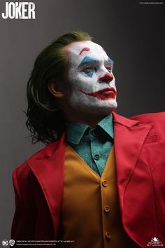 a man with green hair wearing a red jacket and clown makeup