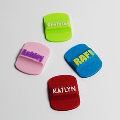 four different colored plastic magnets with words on them