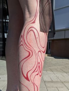 a woman's legs with red and white lines painted on them, in front of a building