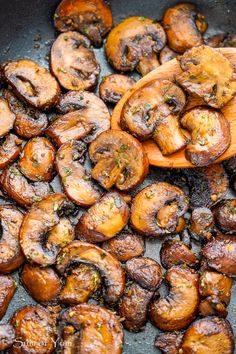 mushrooms being cooked in a pan with a wooden spoon