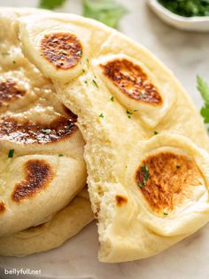 two pita breads cut in half on top of a white plate with parsley