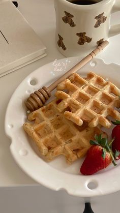 waffles, strawberries and honey on a plate with a cup of coffee