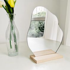 a vase filled with yellow flowers next to a mirror on top of a white table