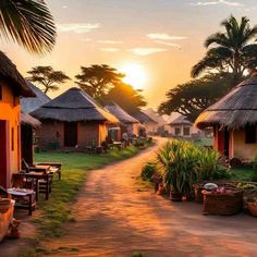 the sun is setting in front of some huts with thatched roofs and palm trees