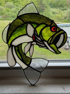 a stained glass fish sitting on top of a window sill