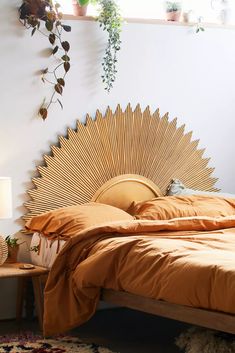 a bed with an orange bedspread in a bedroom next to a plant filled wall