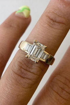 a woman's hand with a ring on it that has three baguettes