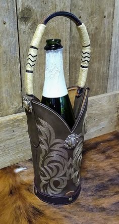 a wine bottle in a leather bucket with an intricate design on the front and sides